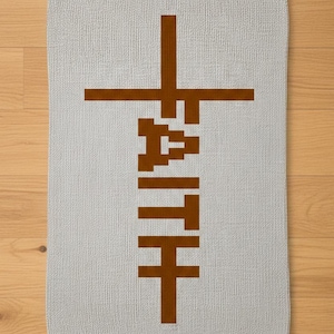 Könnte beinhalten: Ein hellgraues rechteckiges Handtuch mit dem Wort "FAITH" in braunen Blockbuchstaben. Das "F" und das "T" bilden ein Kreuz. Das Handtuch besteht aus einem strukturierten Material und liegt auf einer Holzoberfläche.