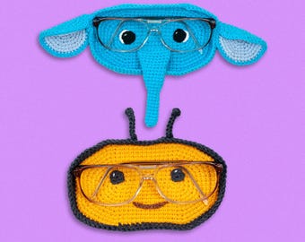 May include: Two crocheted eyeglass holders, one shaped like an elephant and the other shaped like a bee. The elephant holder is blue with a light blue nose and ears. The bee holder is yellow with black accents and a smiling face.