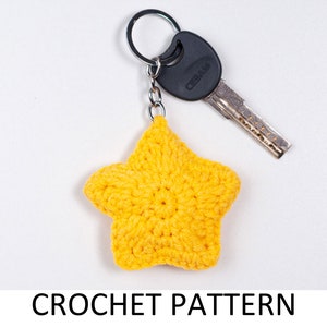 May include: A yellow crocheted star keychain attached to a silver key ring and a black key.