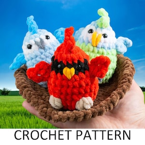 May include: Three crocheted birds in a brown crocheted nest. The birds are a red cardinal, a light blue bird, and a green and light blue bird.