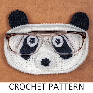 May include: A white and black crochet panda-shaped glasses case with brown-framed glasses inside. The case has black ears, eyes, and nose. The text "CROCHET PATTERN" is at the bottom.