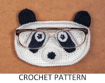 May include: A white and black crochet panda-shaped glasses case with brown-framed glasses inside. The case has black ears, eyes, and nose. The text "CROCHET PATTERN" is at the bottom.