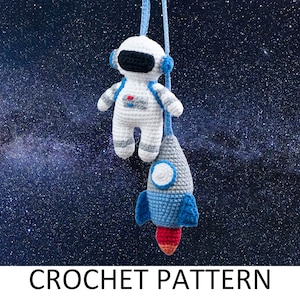 May include: A crochet pattern for a white astronaut with a blue helmet and a blue and grey rocket. The astronaut and rocket are hanging from a string against a dark blue background with white stars.