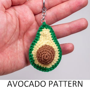 May include: A crocheted avocado keychain with a green outer layer, a yellow inner layer, and a brown pit. The keychain is attached to a silver chain.