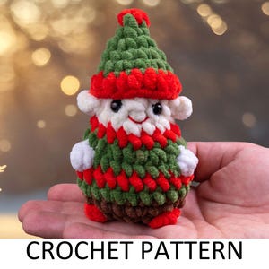 May include: A crocheted elf ornament with a green hat, red and green striped body, and white face. The elf is holding a red and white striped bag.