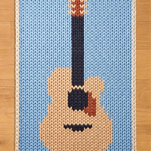 May include: A knitted guitar rug with a light blue background and a cream-coloured border. The guitar is tan with a dark brown neck and a reddish-brown headstock. The rug is a decorative item.