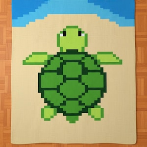 May include: A pixelated turtle blanket featuring a green turtle design on a beige background, with a blue sky border. The turtle has a detailed shell and outstretched flippers. The blanket is likely made of soft material.