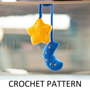 May include: A yellow crocheted star and a blue crocheted crescent moon hang from a rearview mirror.  The star and moon are connected by a string.