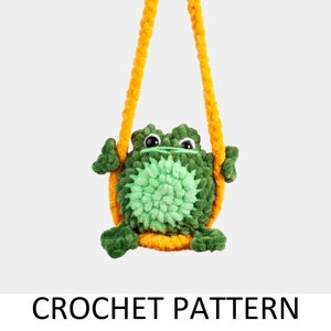May include: A green crocheted frog toy hanging from a yellow crocheted rope. The frog has a green body with a light green belly and black eyes. The frog is sitting on a yellow crocheted ring.