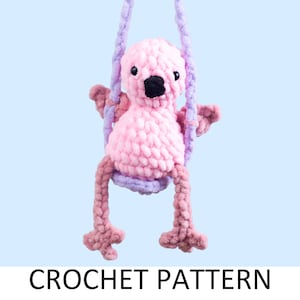 May include: Pink crocheted flamingo toy on a purple swing. The flamingo has black eyes and a black beak. Crochet pattern.