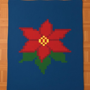 Puede incluir: Una manta azul con un gran diseño de flor de pascua pixelada. La flor es roja con un centro amarillo y hojas verdes. La manta es rectangular y parece estar tejida o crochetada.