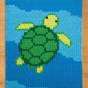 Peut inclure: Carré tricoté représentant une tortue verte et jaune nageant dans un océan bleu. La tortue a une carapace et des nageoires texturées. Le fond est un dégradé de nuances de bleu, créant un effet d'eau.