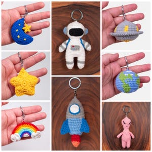 May include: A set of nine crocheted keychains with space-themed designs, including a crescent moon, a star, a planet, a rocket, an astronaut, a rainbow, and an alien.