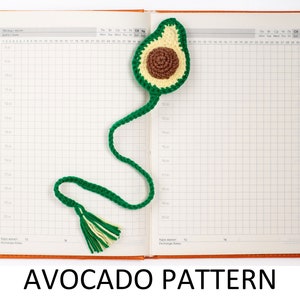May include: A green and brown crocheted avocado bookmark with a tassel. The bookmark is laying open on a page of a gridded notebook.