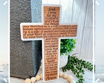 Könnte beinhalten: Ein Holzkreuz mit weißem Hintergrund und braunen Holzakzenten. Das Kreuz trägt eine Botschaft, die lautet: "Herr, ich bete für meinen Mann, und ich vertraue darauf, dass er durch dein Wort ein Mann von Integrität ist, der Rechtschaffenheit, Gottesfurcht, Glauben und Liebe verfolgt. Er ist ein Mann der Weisheit und hält sich an die Wahrheit deines Wortes wie an kostbare Juwelen. Schütze seinen Geist vor den Einflüssen dieser Welt und hilf ihm, stark gegen Versuchungen zu sein. Ich bete, dass du ihn zu einem geistlichen Führer in unserem Zuhause erhebst, und dass er mich lieben wird, wie Christus die Kirche geliebt hat. Amen."