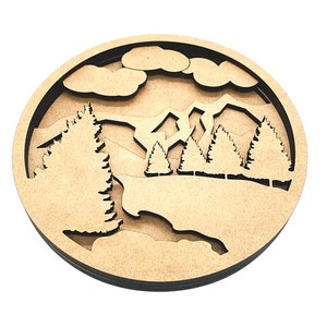 May include: A wooden wall decor featuring a layered design of a mountain range with trees and clouds. The design is cut out of the wood, creating a 3D effect.