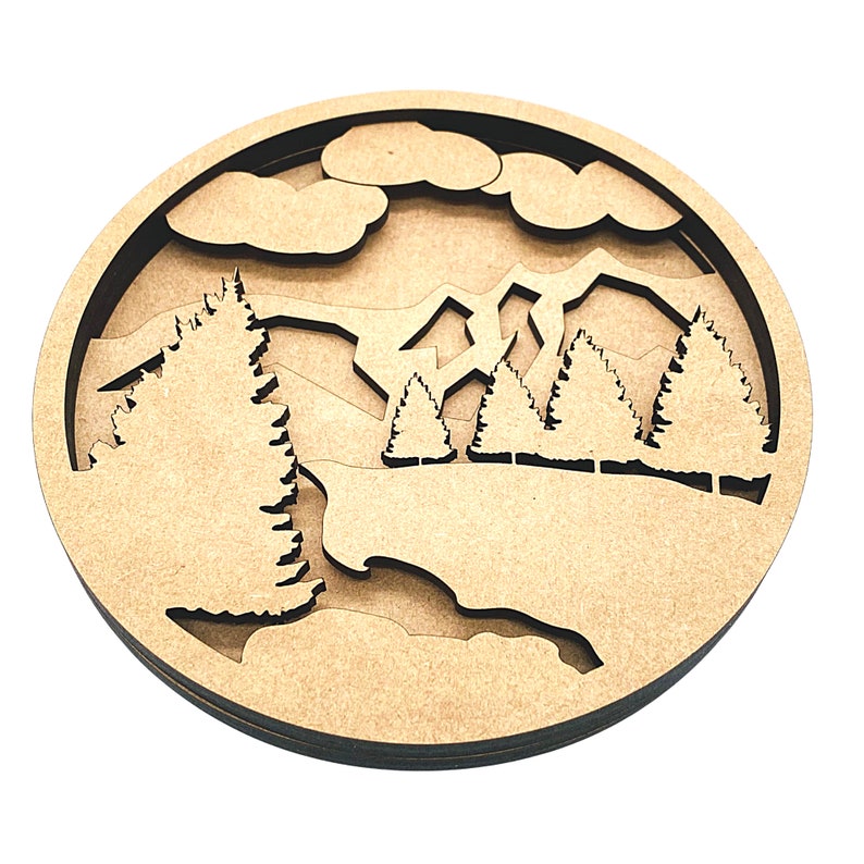 May include: A wooden wall decor featuring a layered design of a mountain range with trees and clouds. The design is cut out of the wood, creating a 3D effect.
