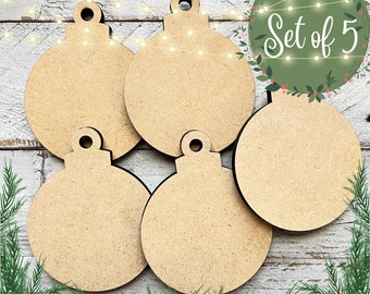 May include: Set of five unfinished wooden ornaments shaped like Christmas tree ornaments. The ornaments are round and have a hole at the top for hanging.