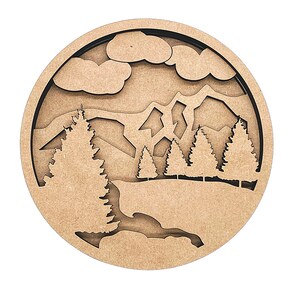 May include: A round wooden wall decor with a cutout design of a mountain landscape with trees and clouds. The wood is a light brown color.