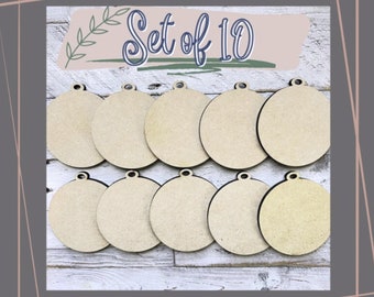 May include: Set of 10 unfinished wooden round ornaments with a hole for hanging. The ornaments are light brown and have a smooth surface.