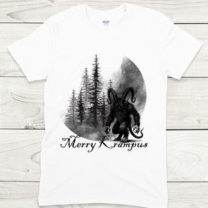 May include: White t-shirt with a black and white illustration of a Krampus figure standing in a forest with the text "Merry Krampus" below.