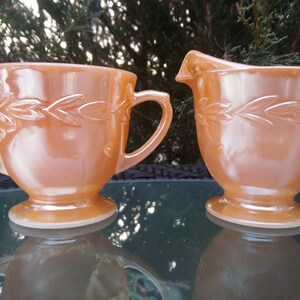 以下が含まれることがあります： 葉のデザインが施された、ピーチ色のミルクガラス製のクリーマーとシュガーボウル2個のヴィンテージセット。