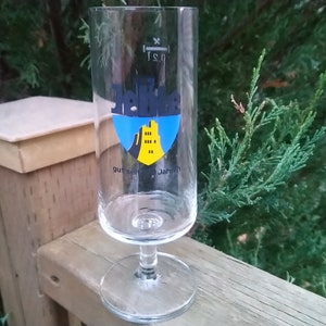 May include: A clear glass beer stein with a blue and yellow logo featuring a castle and the text "Jahn" and "Burgbrauerei Jahn" printed on the side.