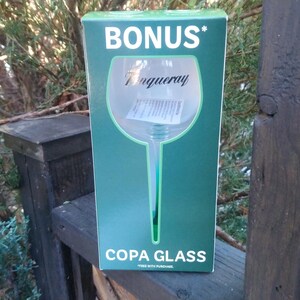May include: A green box with the word "BONUS" in white at the top. The box features a large illustration of a copa glass with the Tanqueray logo. The words "COPA GLASS" are printed at the bottom.