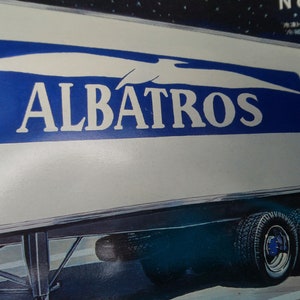 May include: A white refrigerated trailer with the word "ALBATROS" in large blue letters. The trailer has multiple wheels and tires. The image also includes Japanese text.