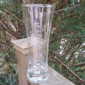 May include: A clear glass beer mug with the word "Heineken" embossed on the side.