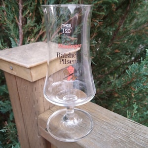 May include: A clear glass beer stein with a red and black logo that says "Ratsche Pilsener" and "Wienerlager".