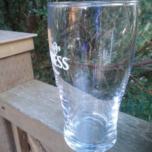 May include: A clear glass pint glass with the word "Guinness" printed on the side.