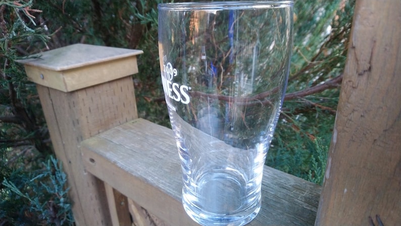 May include: A clear glass pint glass with the word "Guinness" printed on the side.