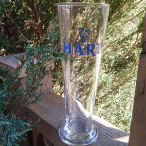 Może przedstawiać: Szklany kufel do piwa z przezroczystego szkła z niebiesko-złotym logo HARP Lager.