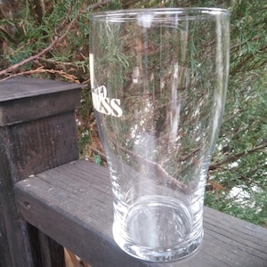 Puede incluir: Un vaso de pinta de vidrio transparente con la palabra "Guinness" impresa en el lateral.