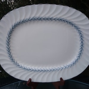 Pode incluir: Travessa oval branca com um design de folhas azul e branco ao redor da borda.
