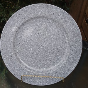 Puede incluir: Un plato de servicio grande, redondo y gris con un acabado moteado. El plato tiene un borde elevado y un centro blanco liso.