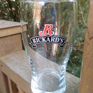 May include: A clear glass beer mug with a red "R" and the words "Rickard's" printed on the front.
