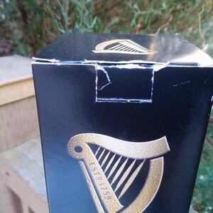 May include: A black cardboard box with a gold harp logo and the text "ESTD 1759".