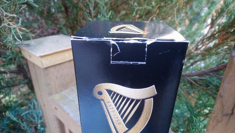 May include: A black cardboard box with a gold harp logo and the text "ESTD 1759".