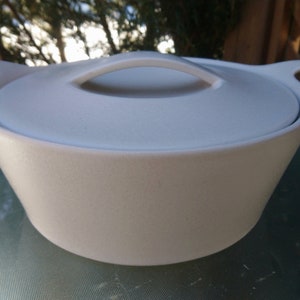 May include: White ceramic casserole dish with a lid and two handles. The dish has a textured surface.