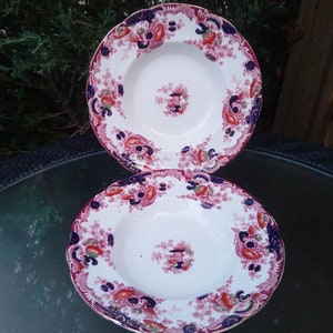 May include: Two vintage soup bowls with a floral pattern in shades of red, blue, and gold. The bowls are stacked on top of each other.