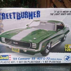 Puede incluir: Un kit de maqueta de un Chevrolet Camaro SS 427 L-72 Baldwin Motion verde de 1969 con una franja blanca en el capó. La caja presenta el texto "STREETBURNER" y "IT GETS MEAN WHEN THE LIGHT GOES GREEN!" La caja también incluye la escala del modelo de coche, 1:25.