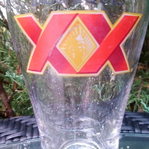 May include: A clear glass beer mug with a red and yellow logo that says "XX" on it.