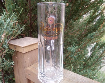 Op de afbeelding: Een helder glazen bierglas met een gouden logo met de tekst "Paderborner Pilsener" aan de voorkant.