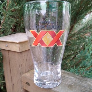 May include: A clear glass beer mug with a red and gold logo that says "Cerveza Dos Equis" and "XX".