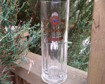 Op de afbeelding: Een helder glazen bierglas met een gouden en blauw logo met de tekst "Radeberger".
