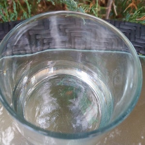 K&ouml;nnte beinhalten: Ein klares Glas, gef&uuml;llt mit Wasser, steht auf einem schwarzen und wei&szlig;en Korbtisch.