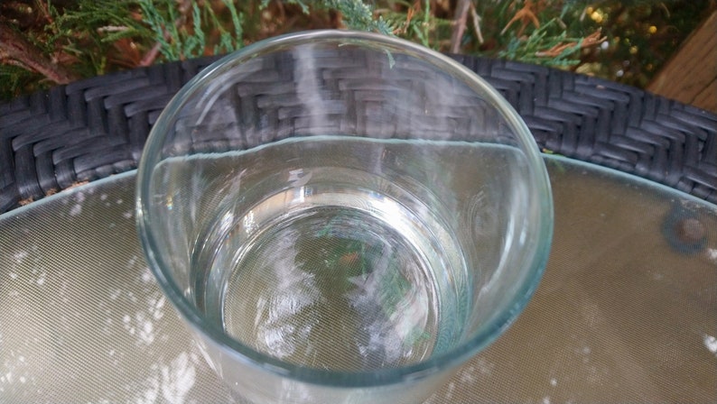 K&ouml;nnte beinhalten: Ein klares Glas, gef&uuml;llt mit Wasser, steht auf einem schwarzen und wei&szlig;en Korbtisch.