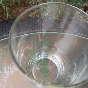 Puede incluir: Un vaso de beber de vidrio transparente con una base gruesa y un borde ancho. El vaso est&aacute; vac&iacute;o y parece estar limpio.